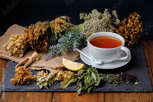 Herbal tea in white cup on black background. Side view.