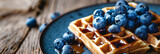 Delectable Belgian waffles adorned with fresh blueberries served on a rustic dark plate
