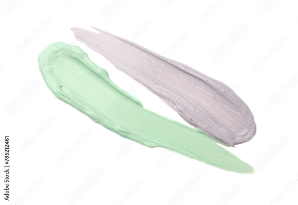 Strokes of green and purple color correcting concealers on white background, top view