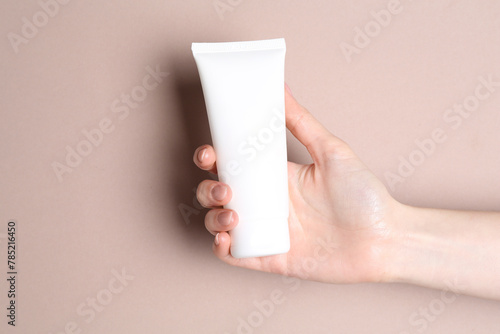 Woman with tube of cream on beige background, closeup © New Africa