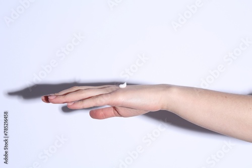 Woman with cream on her hand against white background  closeup