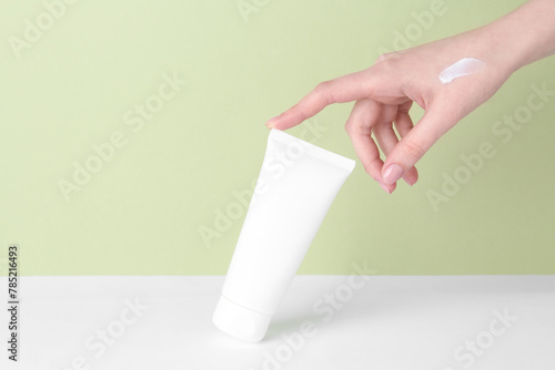 Woman with tube of cream on color background, closeup