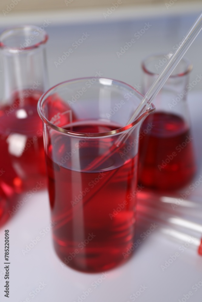 Laboratory analysis. Different glassware with red liquid on white table indoors, closeup Laboratory analysis. Different glassware with red liquid on white table indoors, closeup
