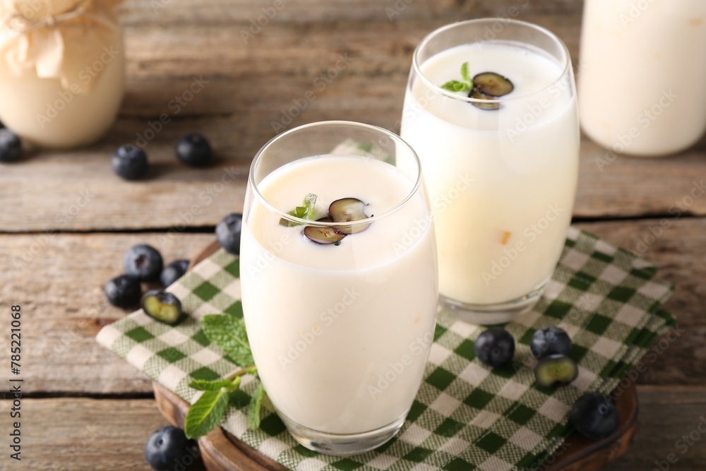 Tasty yogurt in glasses and blueberries on wooden table, closeup Tasty yogurt in glasses and blueberries on wooden table, closeup