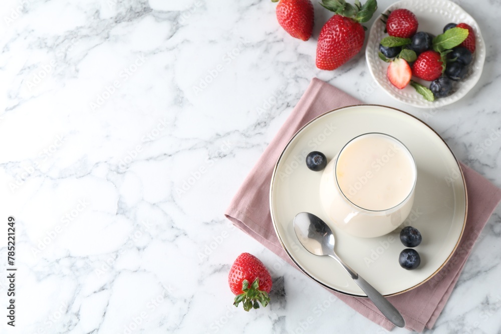 Tasty yogurt in glass and berries on white marble table, flat lay. Space for text Tasty yogurt in glass and berries on white marble table, flat lay. Space for text