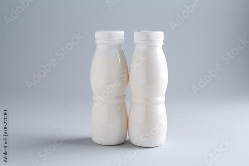 Tasty yogurt in bottles on light grey background