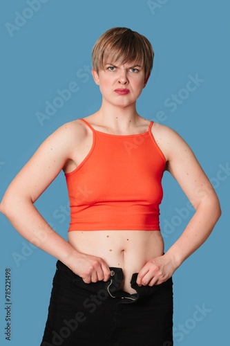 Portrait of an overweight woman, on which clothes do not fit, on a colored background. The concept of a healthy body, body positive. Vertical frame.