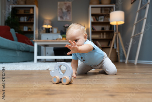 Photography Young happy adorable baby girl or boy sitting on the floor of apartment playing with his or her favorite toy