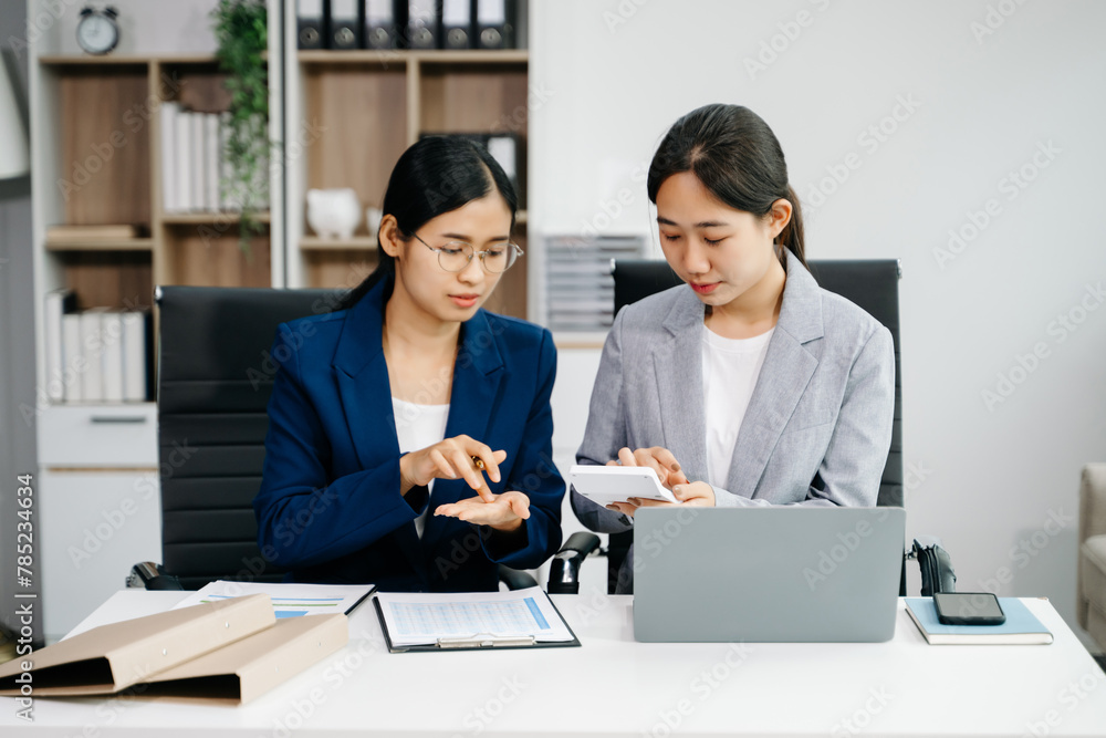 Businesswomen work and discuss their business plans. A women employee explains and shows her colleague in office. Businesswomen work and discuss their business plans. A women employee explains and shows her colleague in office.