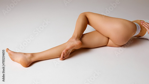 Cropped photo of young, slim female body, smooth, long legs, buttocks against white studio background. Woman in lingerie. Concept of beauty and health, depilation, anti-cellulite program, dieting.