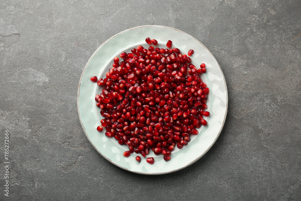 Tasty ripe pomegranate grains on grey table, top view Tasty ripe pomegranate grains on grey table, top view
