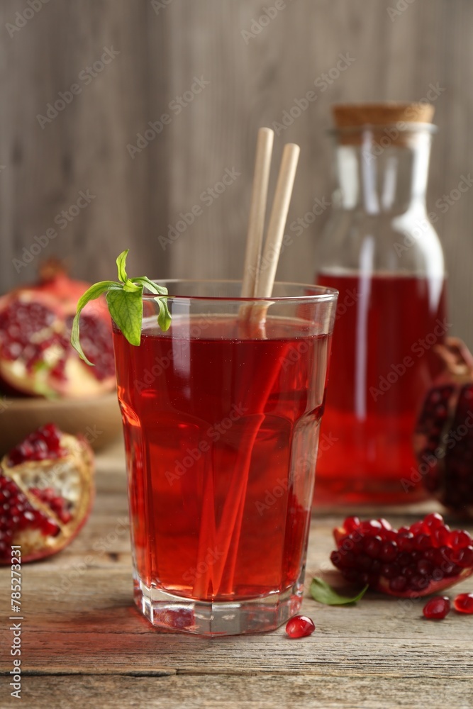 Tasty pomegranate juice in glass and fresh fruits on wooden table Tasty pomegranate juice in glass and fresh fruits on wooden table