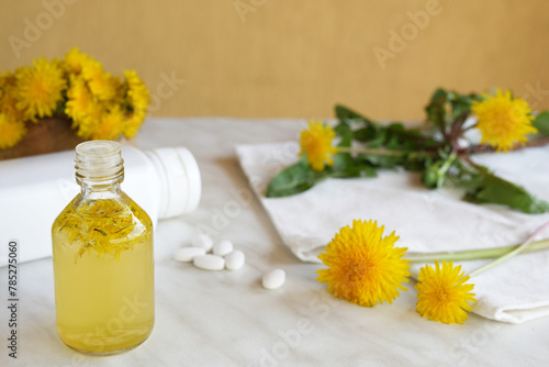 Bottle of essential oil with flowers dandelions. Healing herbs. Dandelions tinctures. Fragrant flower for perfumery  cosmetics production. Side view. Space for text.