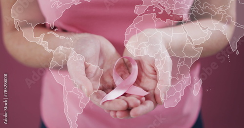 Image of world map over caucasian woman with pink ribbon on pink background