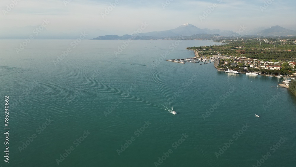 Beautiful panoramic drone view of Lake Garda. High top view of water landscape with hills of mountains and city on sunny summer day. Peschiera del Garda, Italy