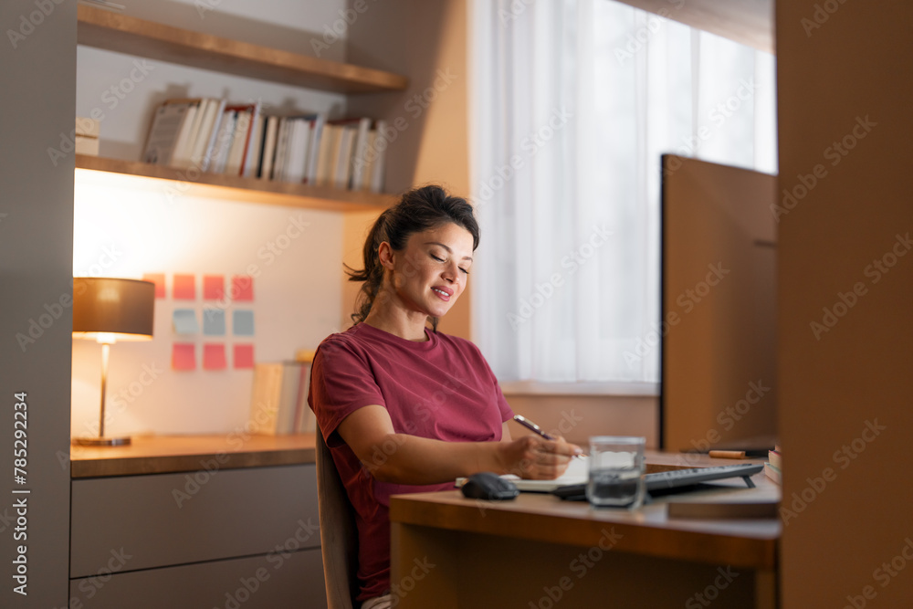 A diligent adult woman taking notes on transaction records and working from home A diligent adult woman taking notes on transaction records and working from home
