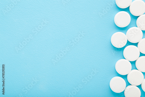 White pills of c vitamins on light blue table background. Pastel color. Closeup. Nutritional supplements. Empty place for text. Top down view.