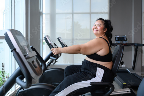 Asian overweight women exercising on the exercise bike in indoor fitness club. Healthy and Fitness concept. Weight loss workout, healthy lifestyle concept