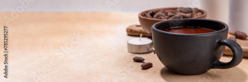 Ceremonial Cacao drink. Hot ceremonial chocolate in black cup with cocoa beans. Woman hands holding cocoa mug. Organic healthy chocolate drink prepared from beans, without creamer, sugar or toppings