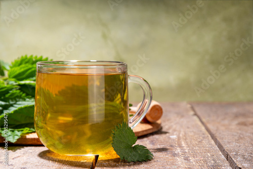 Nettle Tea hot plant drink in transparent glass cup. Organic natural herbal tea without caffeine, made with organic raw nettle leaves. Alternative herbal medicine. Stinging nettles, urtica.