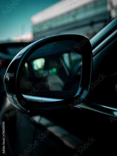 car rear view side mirror. partial interior reflection. out of focus background