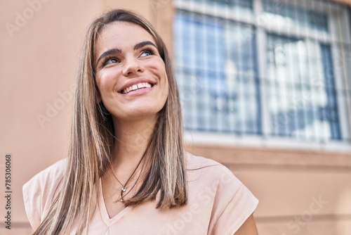 Young beautiful hispanic woman smiling confident looking to the sky at street