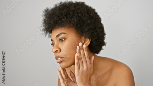 Portrait of a contemplative african american woman with curly hair isolated against a white background, touching her face gently.
