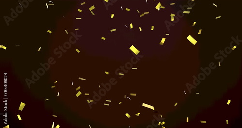 Image of gold confetti floating over red spotlight on black background