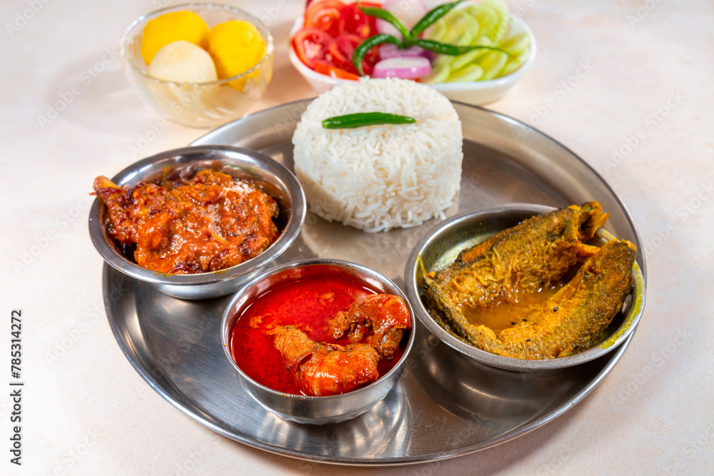 Bengali non vegetarian food thali comprising of plain white rice with spicy chicken curry, prawn and fish dishes, along with dessert and salad. Bengali non vegetarian food thali comprising of plain white rice with spicy chicken curry, prawn and fish dishes, along with dessert and salad.