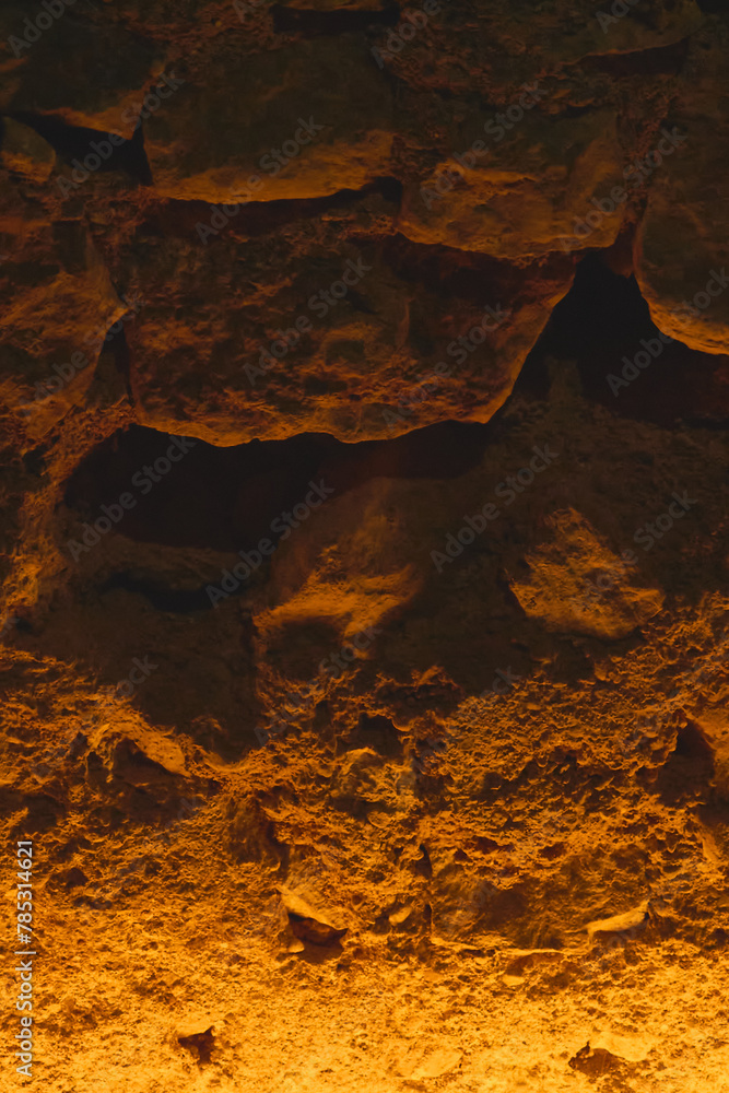 Mysterious image of a cave with amber lighting highlighting intricate details and shadows inviting exploration and discovery.