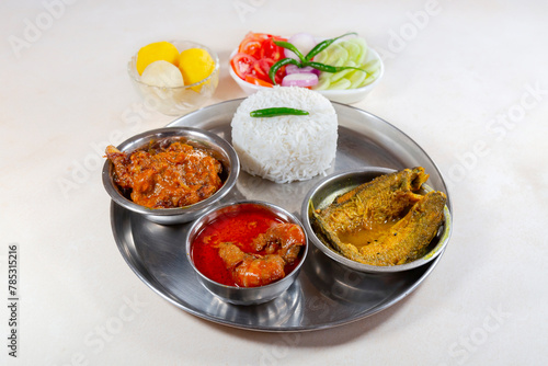 Bengali non vegetarian food thali comprising of plain white rice with spicy chicken curry, prawn and fish dishes, along with dessert and salad © Roop Dey