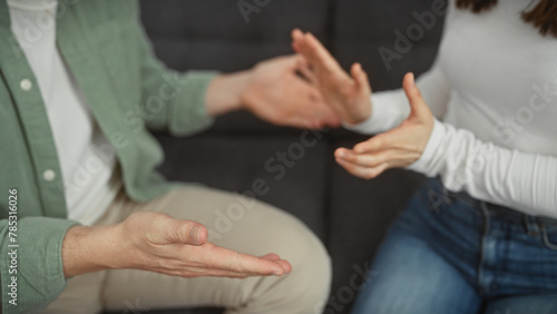 A man and woman engage in a discussion with expressive hand gestures in the living room of a home. photo