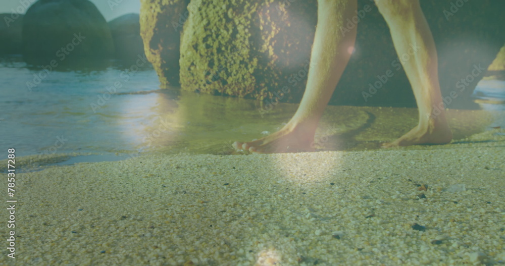Fototapeta premium Image of glowing spots over caucasian woman walking at beach
