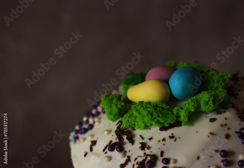 Easter cupcake with white icing and colored decorative eggs close-up