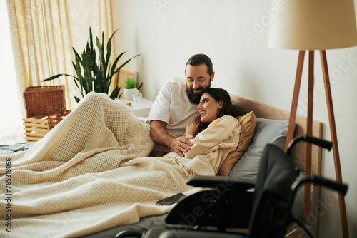 appealing joyous woman with mobility disability lying in bed next to her bearded loving husband photo