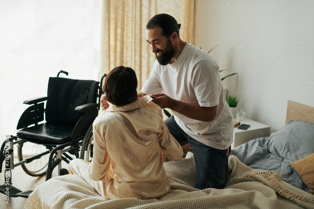 handsome loving man in homewear helping his disabled wife to change into pajama in bedroom at home handsome loving man in homewear helping his disabled wife to change into pajama in bedroom at home