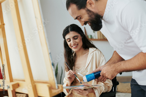 loving jolly husband helping his inclusive good looking wife to paint on easel while at home