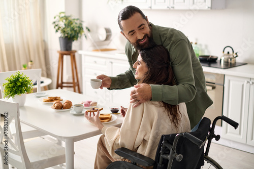 cheerful attractive woman with disability in wheelchair eating breakfast with her loving husband photo