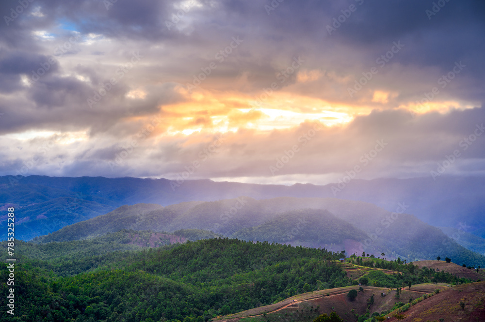 Fototapeta premium amazing dramatic raining clouds in sunset with sun rays over misty mountains landscape 