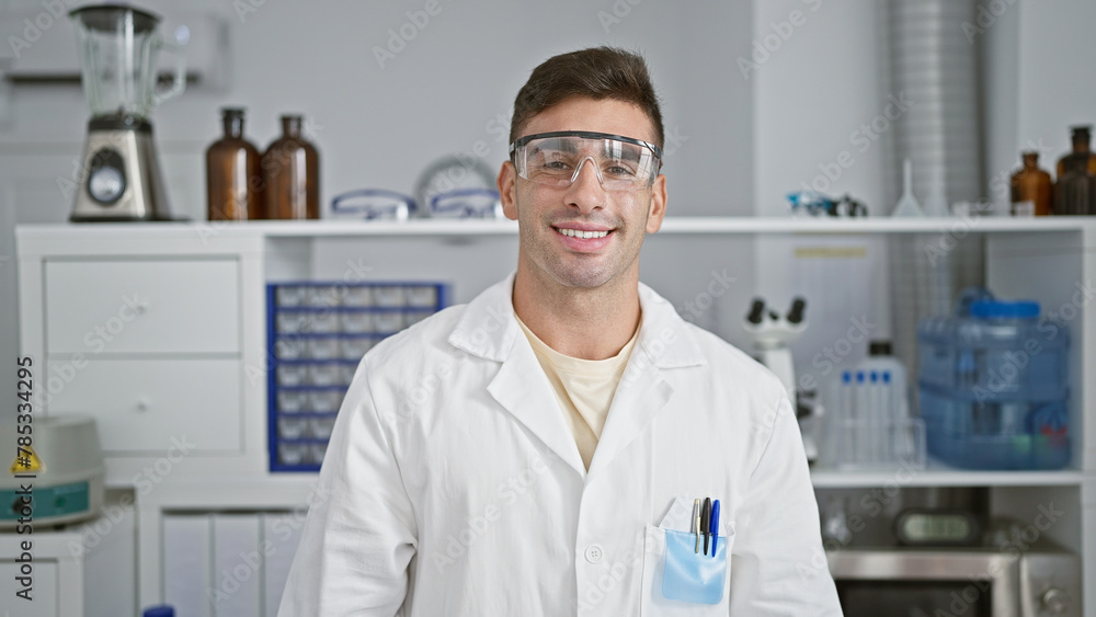 Radiant portrait of a young, handsome hispanic scientist confidently flashing a winning smile while enjoying his work at the lab, carefully wearing security glasses! Radiant portrait of a young, handsome hispanic scientist confidently flashing a winning smile while enjoying his work at the lab, carefully wearing security glasses!