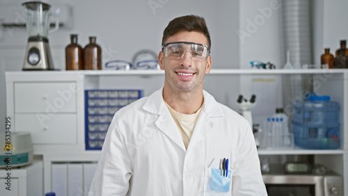 Radiant portrait of a young, handsome hispanic scientist confidently flashing a winning smile while enjoying his work at the lab, carefully wearing security glasses!