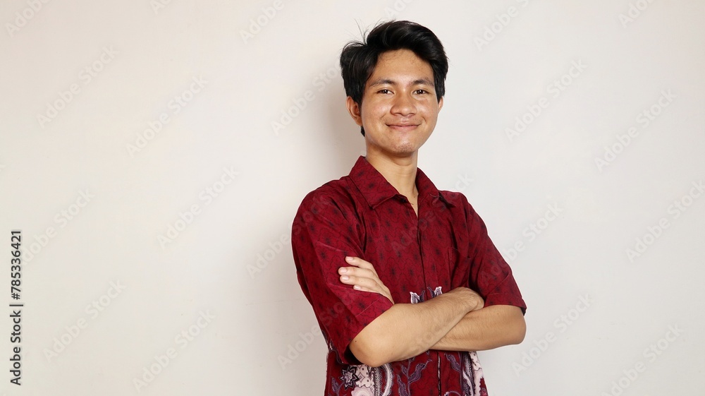 Handsome young Asian man dressed in batik posing crossed arms Handsome young Asian man dressed in batik posing crossed arms