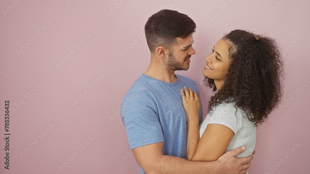 A loving couple embracing each other against a pink background, sharing a moment of affection and togetherness. A loving couple embracing each other against a pink background, sharing a moment of affection and togetherness.