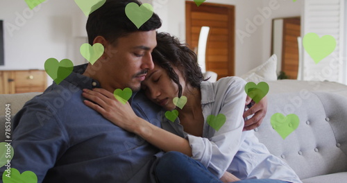 Image of heart icons over biracial couple embracing photo