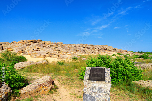 Summer landscape - view of the mound of sandstone boulders with a sign Archaeological site, ancient place of worship, archeological preserve Kamyana Mohyla, Ukraine photo