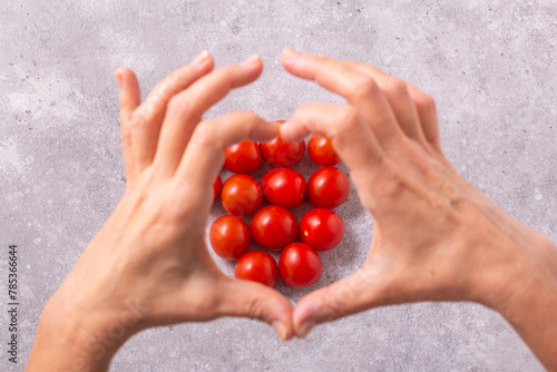 Hands with freshly harvested tomatoes on the table. Womans hands and cherry tomatoes, closeup with selective focus
