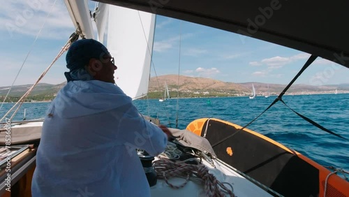 A man on a yacht works with the sails during his summer vacation photo