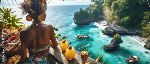 Woman on the background of a tropical bay from a cliff with refreshing drinks