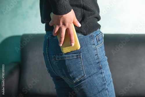 Woman putting smartphone in pocket of jeans. photo