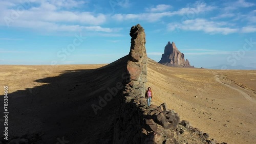 Drone view of a man climbing with joy and happiness and freedom the ShipRock in the Navajo Nation, New Mexico, USA, in a beautiful sunny autumn day with clear blue sky